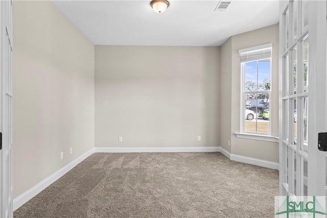 carpeted spare room featuring baseboards and visible vents