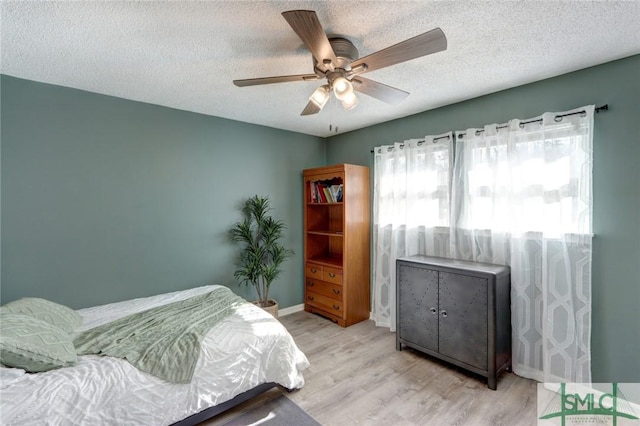 bedroom featuring ceiling fan, light hardwood / wood-style floors, and a textured ceiling