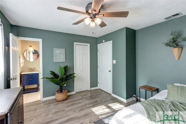 bedroom with a closet, a textured ceiling, light hardwood / wood-style floors, and ceiling fan