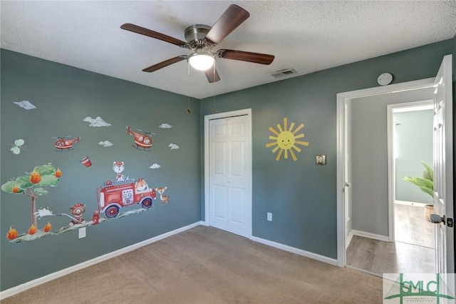 unfurnished bedroom featuring a textured ceiling, ceiling fan, light carpet, and a closet