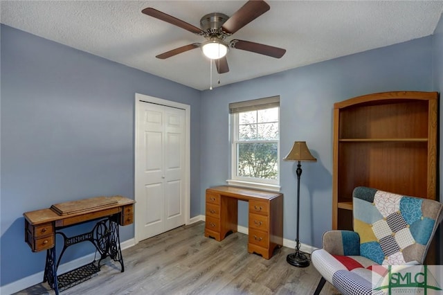 living area featuring ceiling fan, light hardwood / wood-style floors, and a textured ceiling