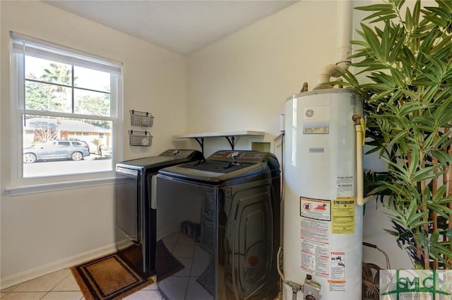 clothes washing area featuring washer and dryer, light tile patterned flooring, and gas water heater