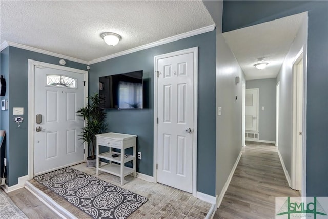 entryway featuring light hardwood / wood-style flooring, a textured ceiling, and ornamental molding