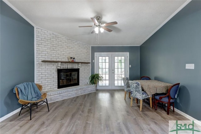 interior space featuring french doors, a textured ceiling, lofted ceiling, a fireplace, and light wood-type flooring