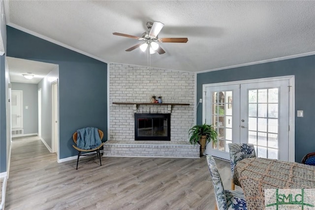 living room featuring vaulted ceiling, french doors, a textured ceiling, and light wood-type flooring