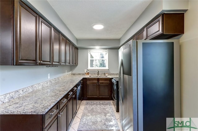 kitchen featuring dark brown cabinets, light tile patterned floors, sink, and appliances with stainless steel finishes