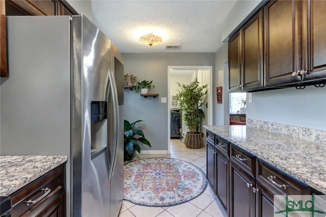 kitchen with stainless steel fridge with ice dispenser, light tile patterned flooring, light stone countertops, and a textured ceiling