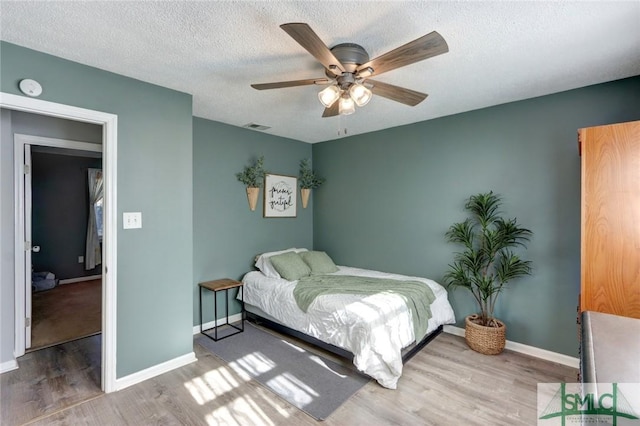 bedroom with ceiling fan, hardwood / wood-style floors, and a textured ceiling