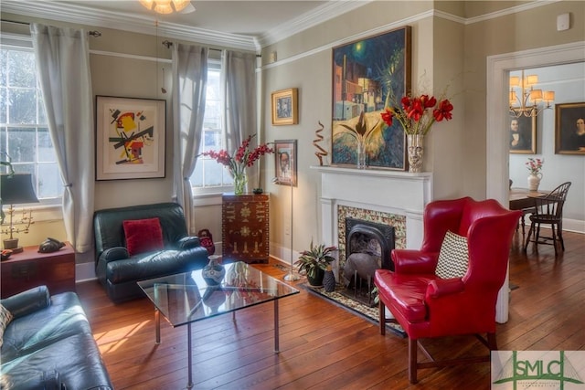 sitting room featuring a fireplace, hardwood / wood-style floors, an inviting chandelier, and ornamental molding