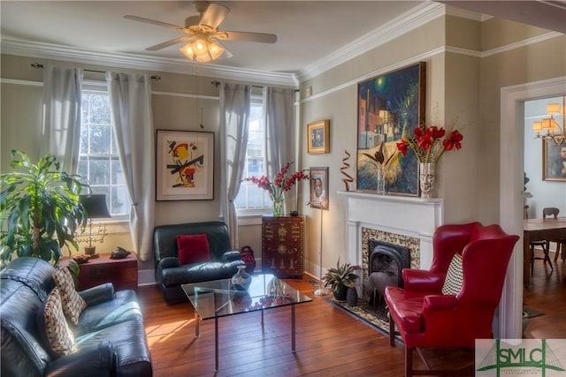 living area featuring ceiling fan with notable chandelier, hardwood / wood-style flooring, ornamental molding, and a tiled fireplace