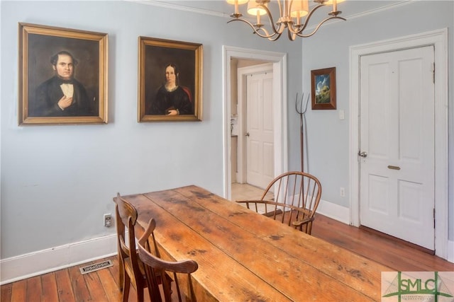 dining area with crown molding, hardwood / wood-style flooring, and an inviting chandelier