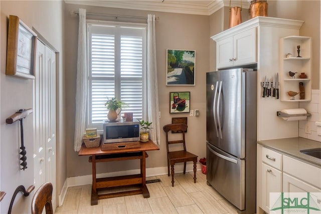 kitchen featuring stainless steel appliances, white cabinetry, and ornamental molding