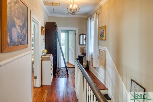 hall featuring dark wood-type flooring, ornamental molding, and a notable chandelier