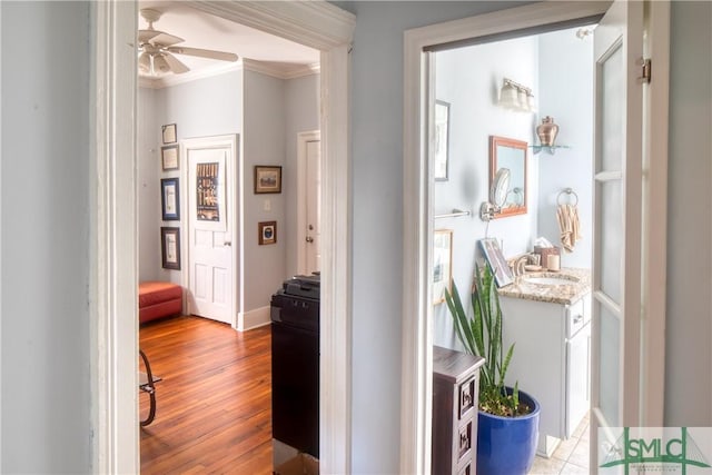 corridor featuring light hardwood / wood-style flooring, ornamental molding, and sink