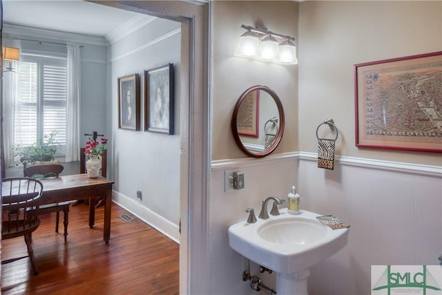 bathroom with hardwood / wood-style floors, ornamental molding, and sink