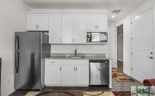 kitchen featuring appliances with stainless steel finishes, light stone counters, white cabinetry, and sink