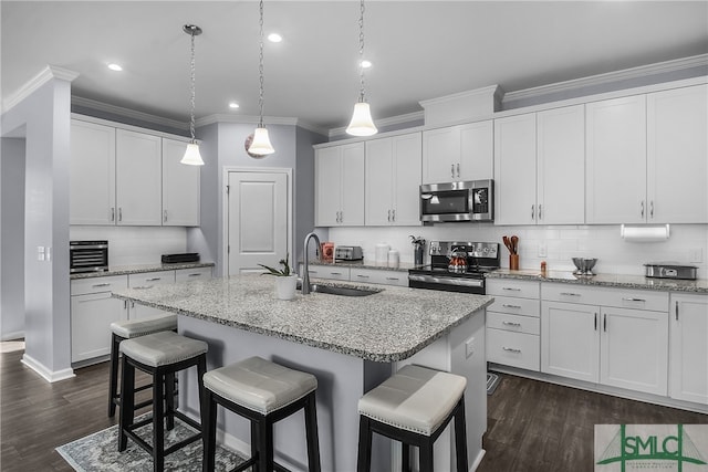 kitchen with stainless steel appliances, white cabinetry, and an island with sink