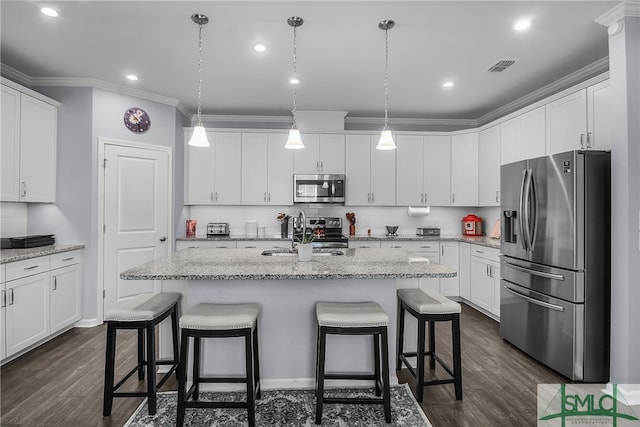 kitchen featuring white cabinetry, light stone countertops, stainless steel appliances, and an island with sink