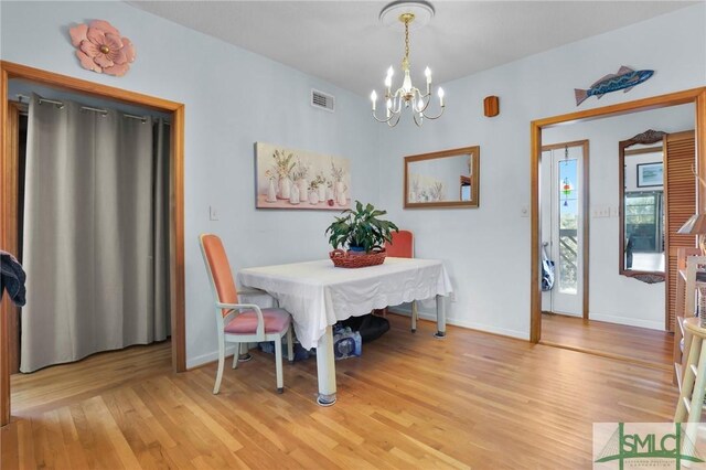 dining area with a notable chandelier and light hardwood / wood-style floors