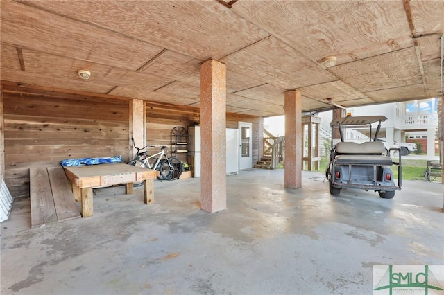 basement with wooden walls, wooden ceiling, and white refrigerator