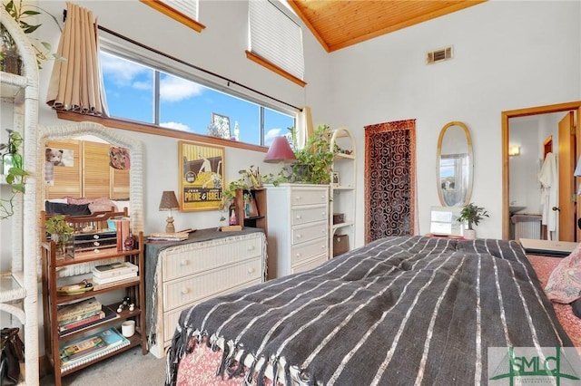 carpeted bedroom featuring a high ceiling, ensuite bath, and wood ceiling