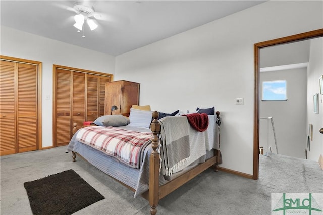 bedroom featuring ceiling fan, light colored carpet, and two closets