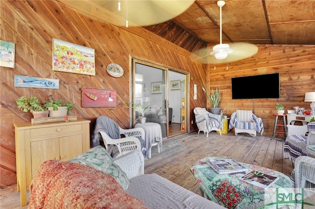 living room with ceiling fan, wooden ceiling, wood walls, wood-type flooring, and vaulted ceiling