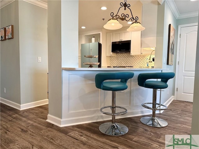 kitchen with a kitchen breakfast bar, stainless steel fridge, decorative light fixtures, and white cabinets