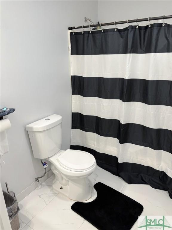 bathroom with a shower with shower curtain and toilet