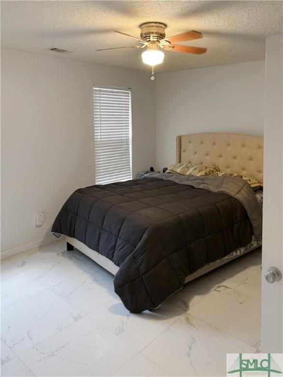 bedroom with ceiling fan and a textured ceiling