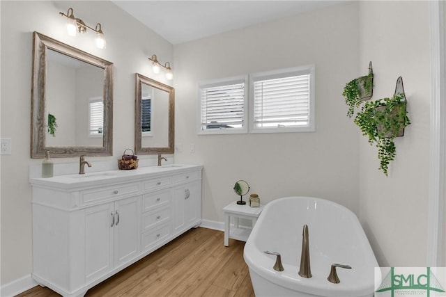 bathroom with a healthy amount of sunlight, hardwood / wood-style floors, vanity, and a bath