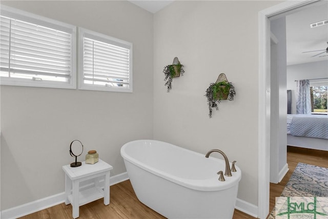 bathroom with ceiling fan, wood-type flooring, and a tub to relax in