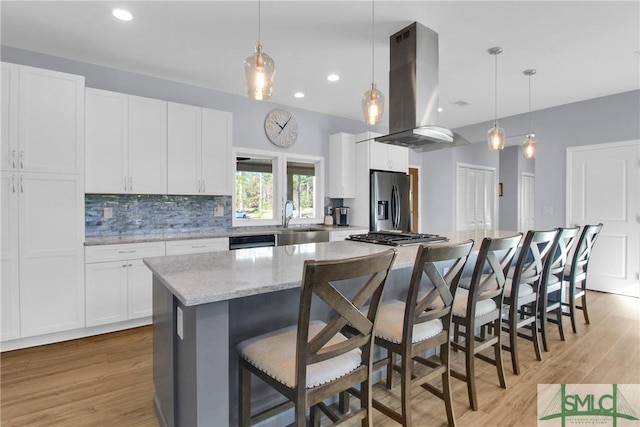 kitchen featuring white cabinets, island range hood, a kitchen island, and stainless steel appliances