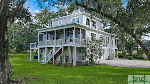 rear view of house featuring a garage, a sunroom, and a lawn