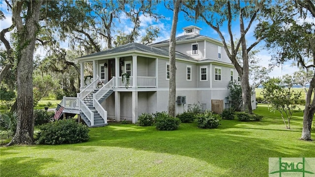 back of house featuring a yard, a porch, and a wall mounted air conditioner