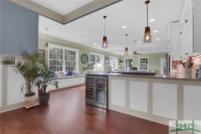 kitchen featuring crown molding, dark hardwood / wood-style flooring, decorative light fixtures, white cabinetry, and beverage cooler