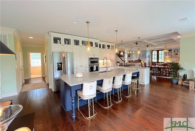 kitchen with pendant lighting, a large island with sink, appliances with stainless steel finishes, sink, and light stone counters