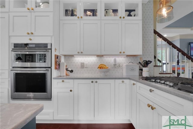 kitchen featuring light stone counters, white cabinetry, stainless steel appliances, and pendant lighting