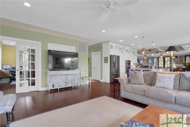 living room with crown molding, dark wood-type flooring, and ceiling fan