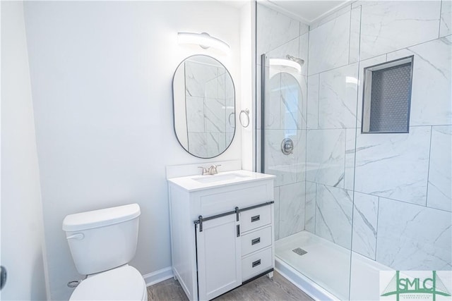 bathroom with toilet, tiled shower, and vanity