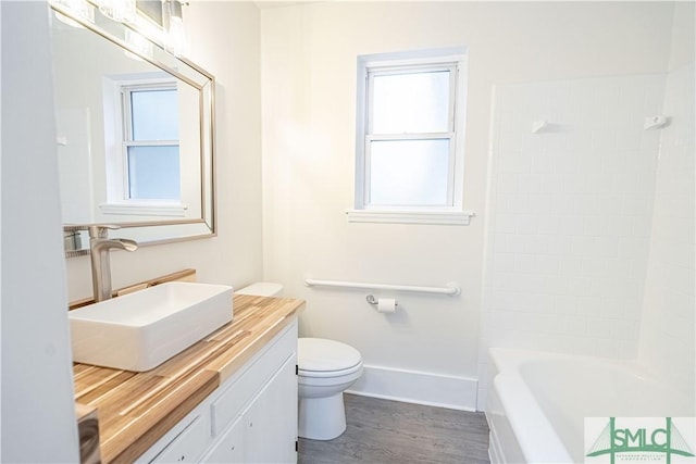 full bathroom with washtub / shower combination, vanity, plenty of natural light, and toilet