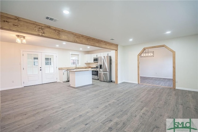 kitchen featuring a kitchen island, white cabinetry, light wood-type flooring, and appliances with stainless steel finishes