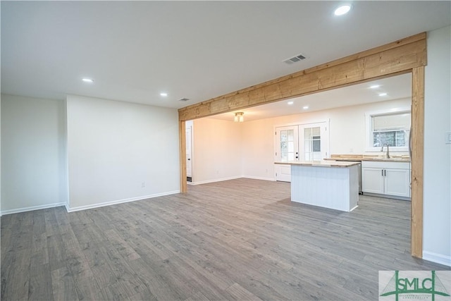 kitchen featuring light hardwood / wood-style floors, a center island, french doors, white cabinets, and sink