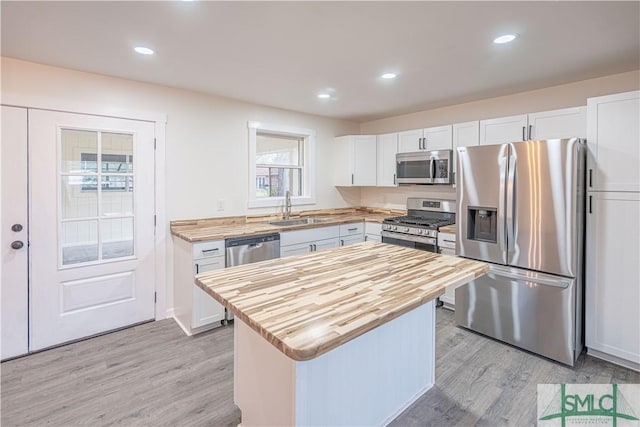 kitchen featuring white cabinetry, appliances with stainless steel finishes, a center island, sink, and light hardwood / wood-style flooring