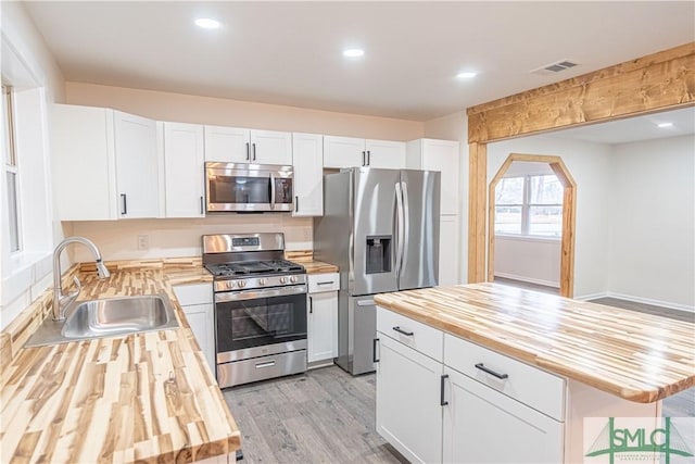 kitchen featuring sink, butcher block counters, appliances with stainless steel finishes, and white cabinetry