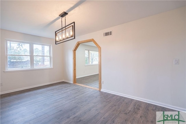 unfurnished room featuring dark hardwood / wood-style flooring, a chandelier, and a healthy amount of sunlight