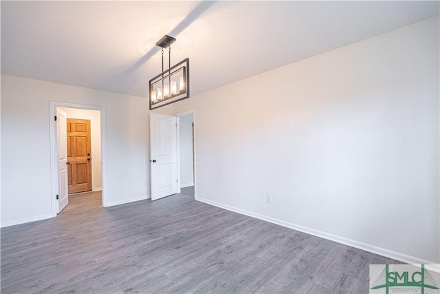 empty room featuring a notable chandelier and dark hardwood / wood-style floors