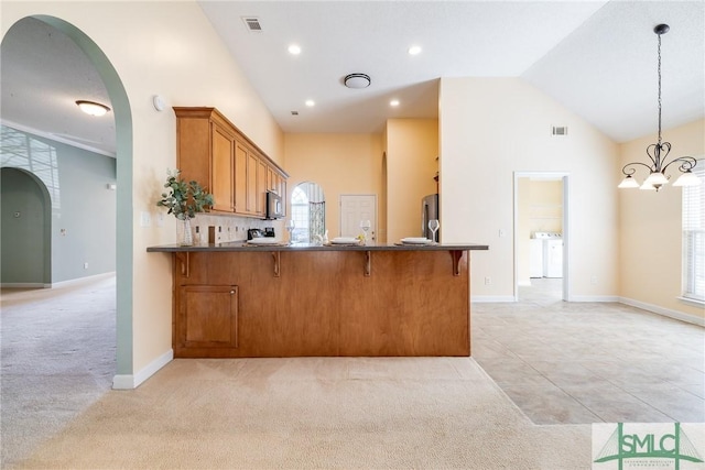 kitchen with a chandelier, stainless steel refrigerator, light colored carpet, kitchen peninsula, and pendant lighting