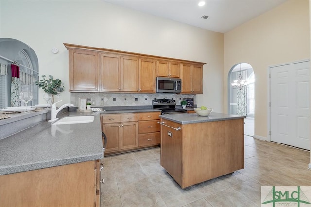 kitchen featuring sink, electric range, a center island, a high ceiling, and a chandelier