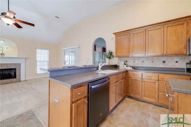 kitchen featuring dishwasher, decorative backsplash, lofted ceiling, a fireplace, and sink